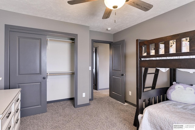 carpeted bedroom with ceiling fan, a textured ceiling, and a closet