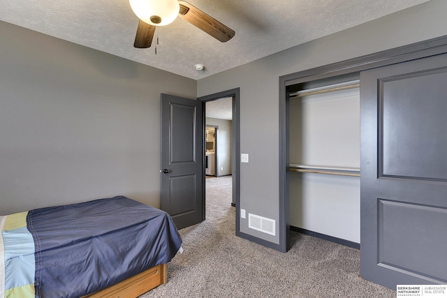 bedroom with ceiling fan, a closet, dark carpet, and a textured ceiling