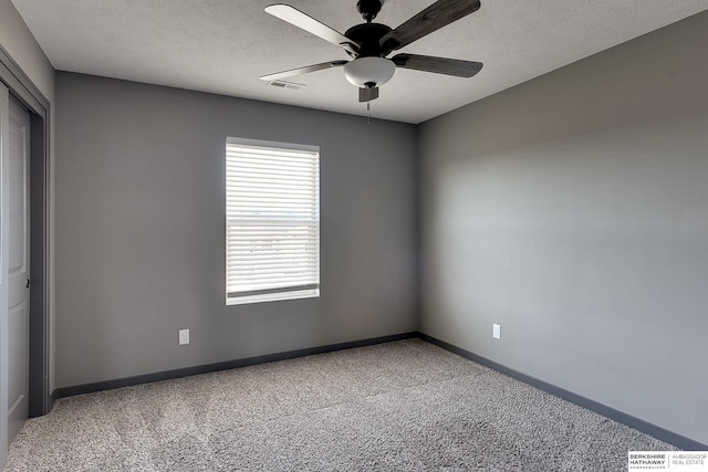 carpeted spare room with ceiling fan and a textured ceiling