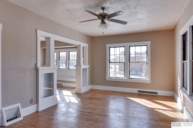 interior space featuring ornate columns, light wood-style flooring, visible vents, and baseboards