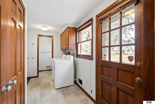 clothes washing area with washer / clothes dryer, plenty of natural light, and cabinets