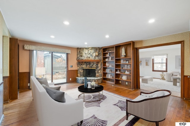 living room featuring a stone fireplace and light wood-type flooring