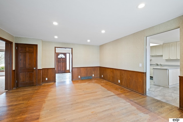 spare room featuring a healthy amount of sunlight, sink, and light hardwood / wood-style flooring