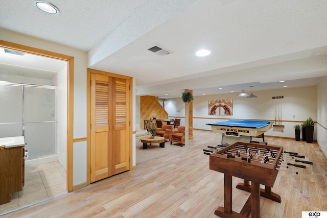 recreation room featuring pool table, a textured ceiling, and light hardwood / wood-style floors