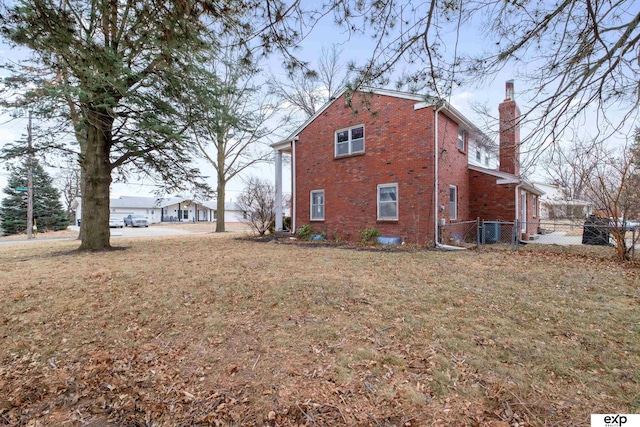 view of side of home featuring cooling unit and a lawn