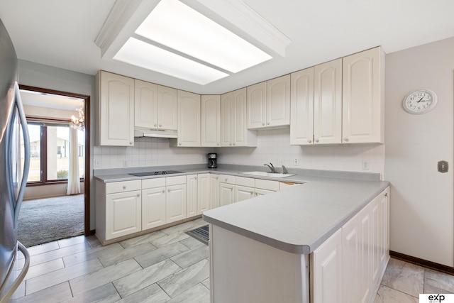 kitchen with sink, stainless steel refrigerator, black electric stovetop, decorative backsplash, and kitchen peninsula