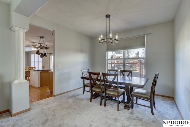 dining space with light carpet, decorative columns, and a chandelier