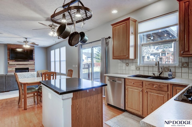 kitchen with pendant lighting, sink, dishwasher, backsplash, and light hardwood / wood-style floors