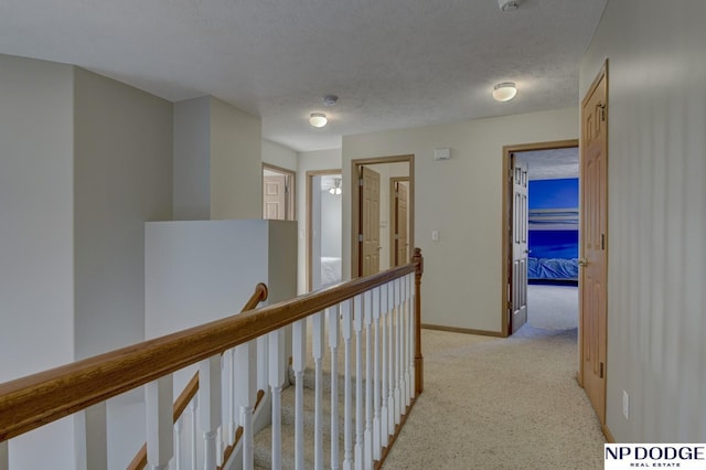 hallway with light colored carpet and a textured ceiling