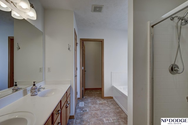 bathroom with vanity, shower with separate bathtub, and a textured ceiling