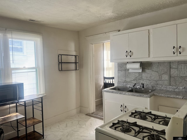 kitchen featuring visible vents, backsplash, black microwave, a sink, and white range with gas stovetop