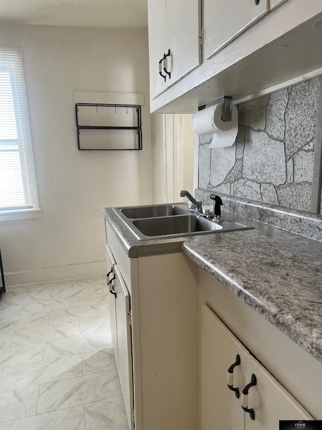 kitchen featuring marble finish floor, baseboards, and a sink