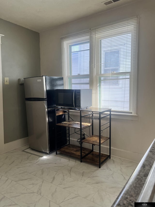 interior space with marble finish floor, plenty of natural light, visible vents, and baseboards