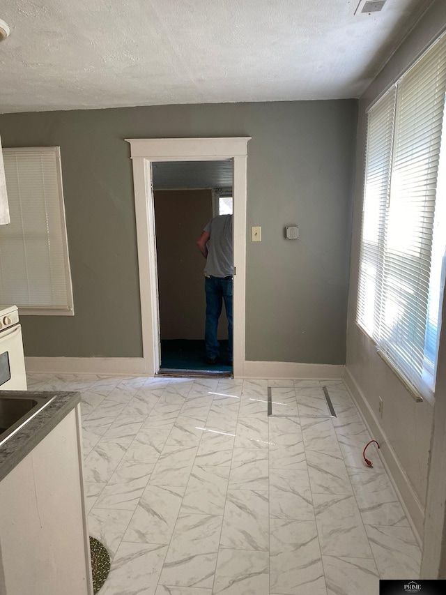 interior space with marble finish floor, visible vents, a textured ceiling, and baseboards