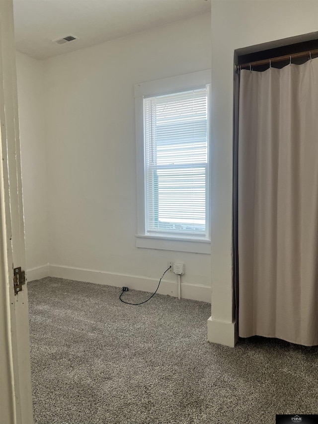 carpeted empty room featuring visible vents and baseboards