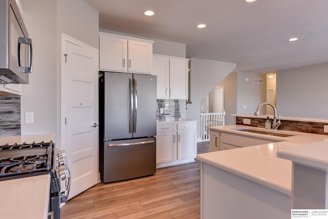 kitchen featuring sink, light hardwood / wood-style floors, white cabinets, and appliances with stainless steel finishes