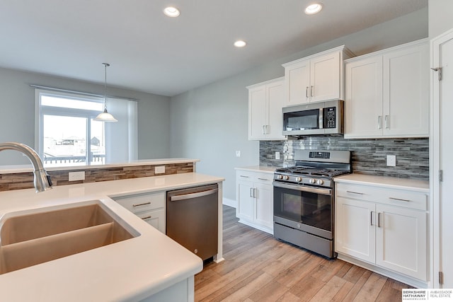 kitchen featuring pendant lighting, sink, white cabinets, and appliances with stainless steel finishes