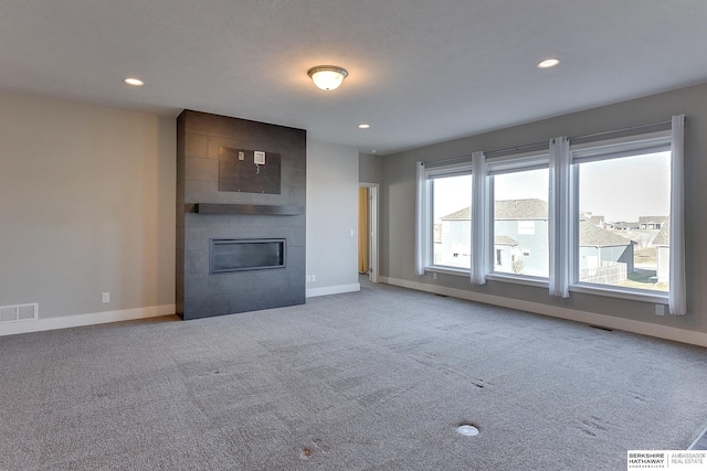 unfurnished living room with a large fireplace and carpet flooring