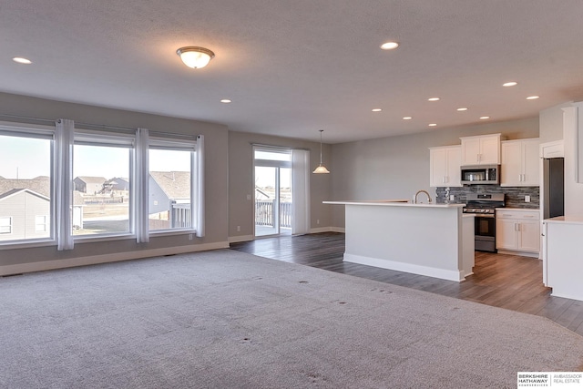 kitchen featuring white cabinetry, a kitchen island with sink, stainless steel appliances, decorative backsplash, and decorative light fixtures