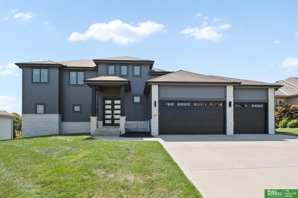 prairie-style home featuring a garage and a front lawn