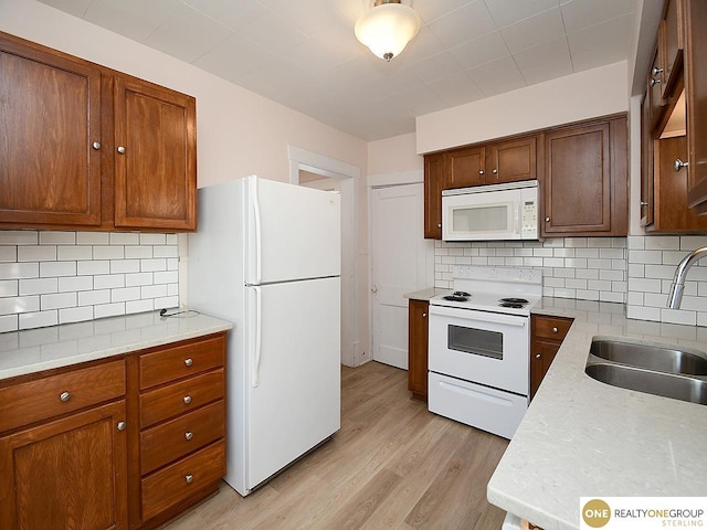 kitchen featuring sink, white appliances, light hardwood / wood-style floors, and decorative backsplash