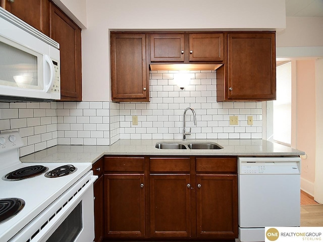 kitchen with tasteful backsplash, sink, white appliances, and light hardwood / wood-style floors