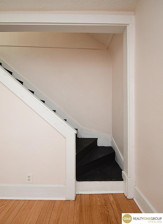 staircase featuring hardwood / wood-style floors and a textured ceiling