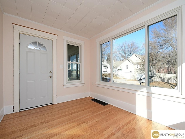 foyer entrance with ornamental molding and light wood-type flooring