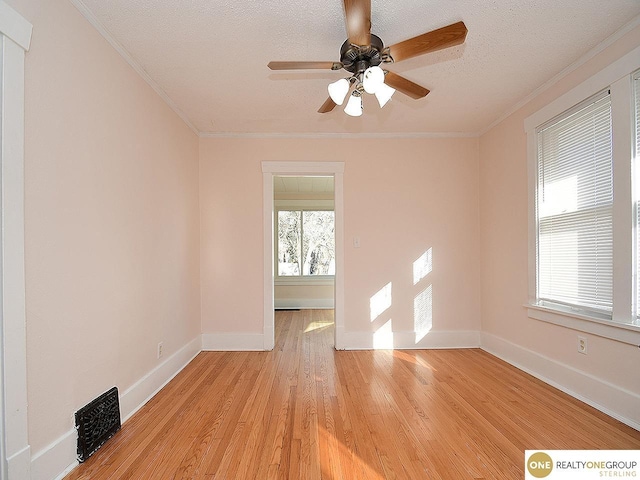 unfurnished room with ceiling fan, ornamental molding, a textured ceiling, and light wood-type flooring