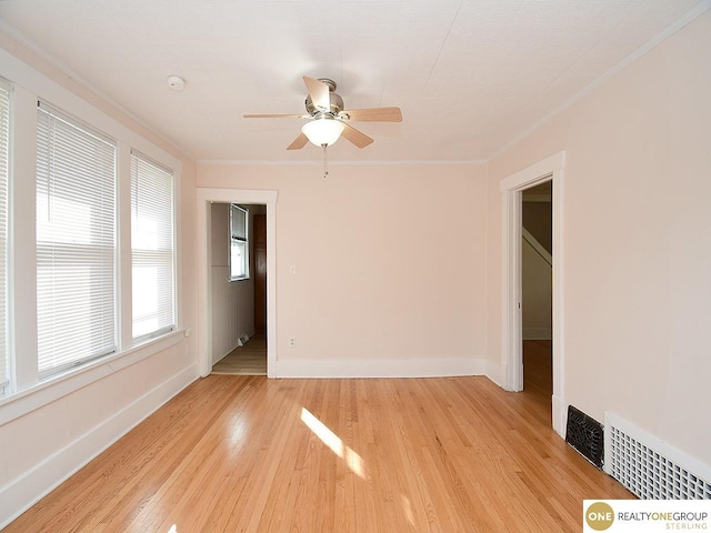 spare room with crown molding, ceiling fan, and light wood-type flooring