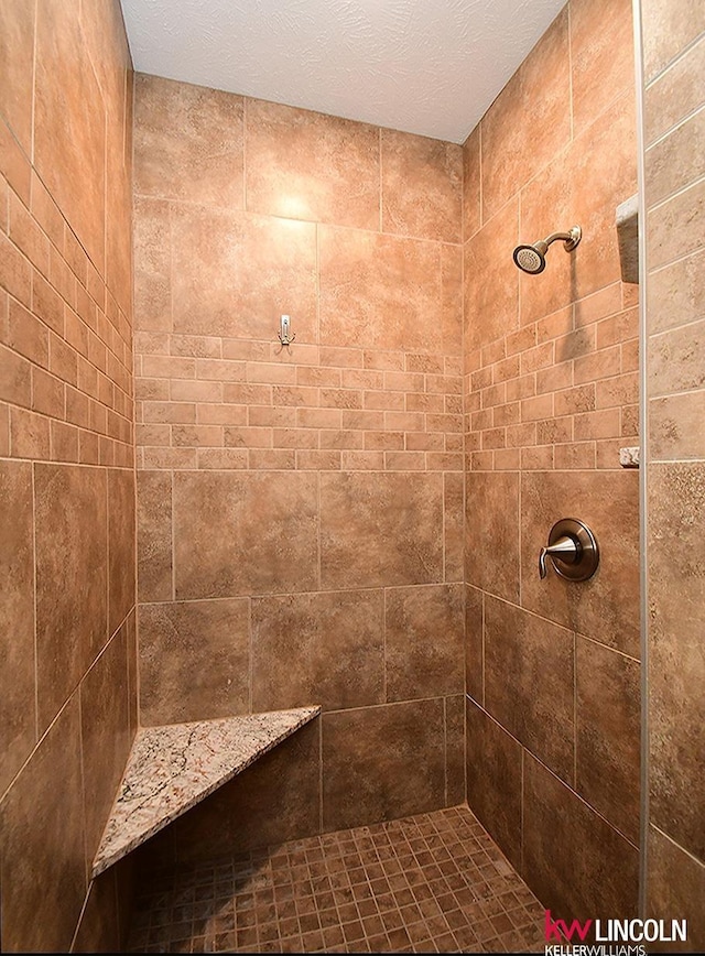 bathroom featuring a tile shower and a textured ceiling