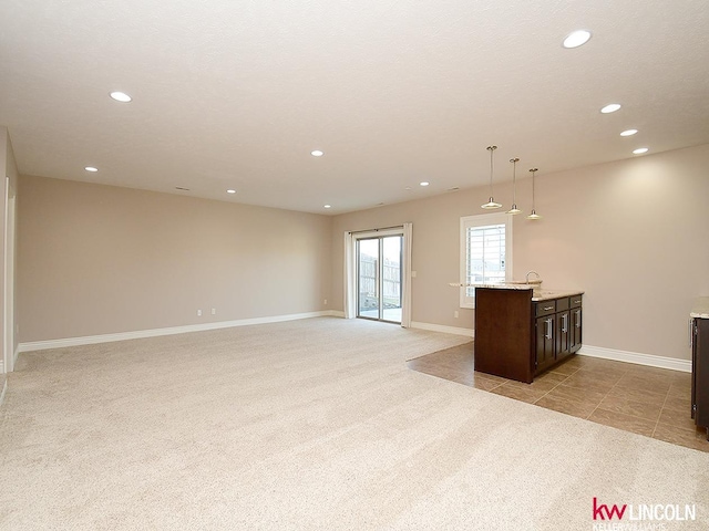 unfurnished living room featuring light carpet, sink, and a textured ceiling