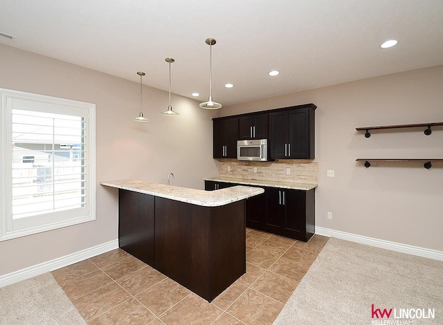 kitchen featuring pendant lighting, backsplash, light tile patterned floors, and kitchen peninsula