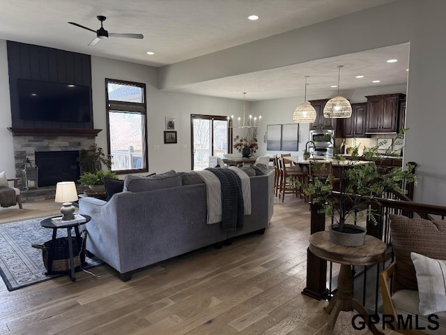 living room featuring a fireplace, dark hardwood / wood-style floors, and ceiling fan with notable chandelier