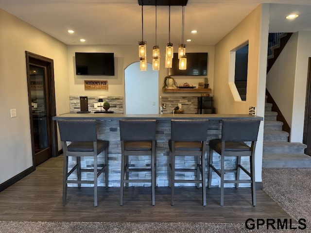 bar with tasteful backsplash, hanging light fixtures, and dark hardwood / wood-style floors