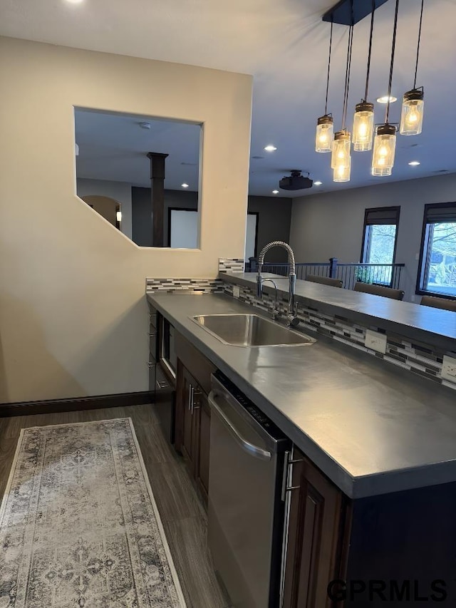 kitchen with sink, dark brown cabinets, stainless steel dishwasher, dark hardwood / wood-style floors, and pendant lighting