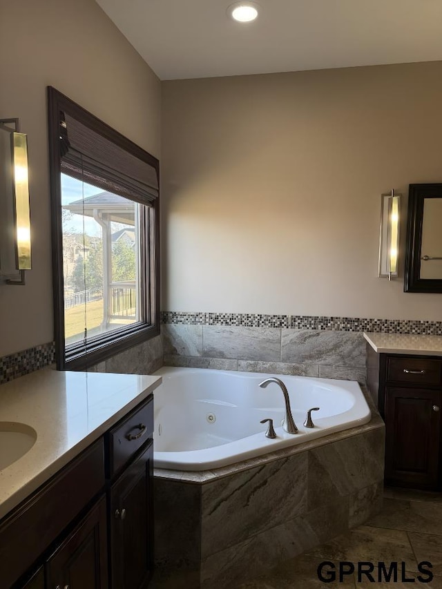 bathroom with vanity and tiled bath