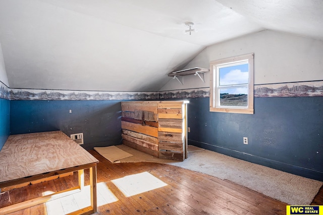 additional living space with hardwood / wood-style flooring and vaulted ceiling