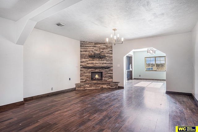 unfurnished living room featuring an inviting chandelier, a fireplace, wood-type flooring, and a textured ceiling