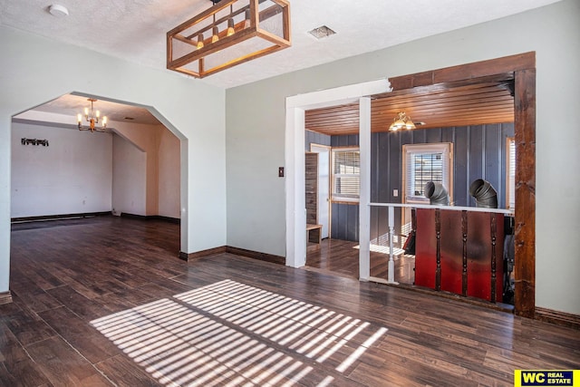 interior space featuring dark wood-type flooring, a notable chandelier, and a textured ceiling