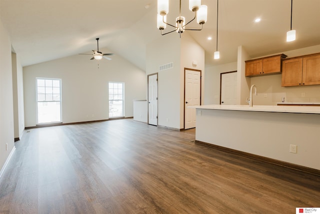 kitchen with dark wood-type flooring, ceiling fan with notable chandelier, high vaulted ceiling, and decorative light fixtures