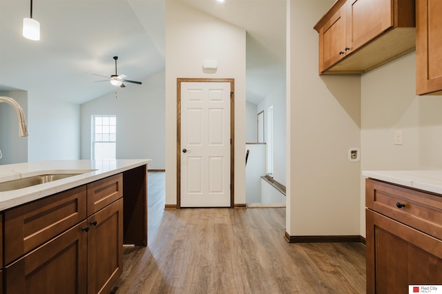 kitchen with sink, vaulted ceiling, hanging light fixtures, light wood-type flooring, and ceiling fan