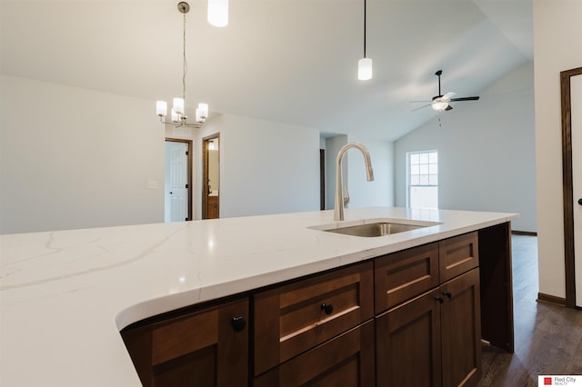 kitchen featuring vaulted ceiling, dark hardwood / wood-style floors, decorative light fixtures, sink, and light stone countertops