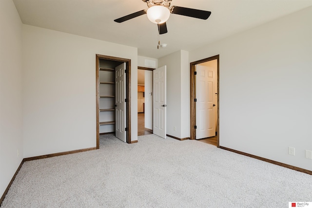 unfurnished bedroom featuring a spacious closet, light carpet, and ceiling fan