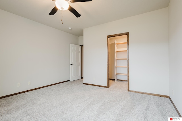 unfurnished bedroom featuring ceiling fan, a spacious closet, a closet, and light carpet