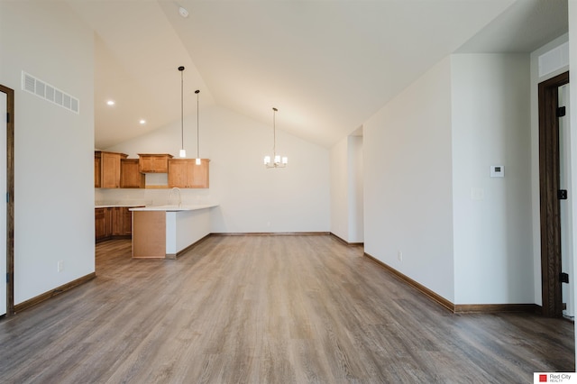 unfurnished living room featuring hardwood / wood-style flooring, high vaulted ceiling, sink, and a chandelier