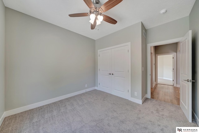 unfurnished bedroom featuring ceiling fan, light colored carpet, and a closet