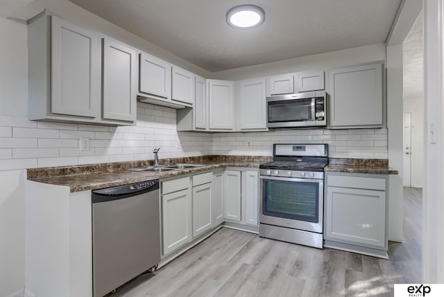 kitchen with white cabinetry, appliances with stainless steel finishes, sink, and light hardwood / wood-style flooring