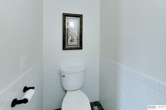 bathroom featuring tile walls and toilet