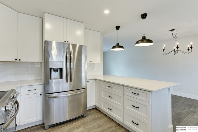 kitchen with decorative light fixtures, light wood-type flooring, appliances with stainless steel finishes, kitchen peninsula, and white cabinets